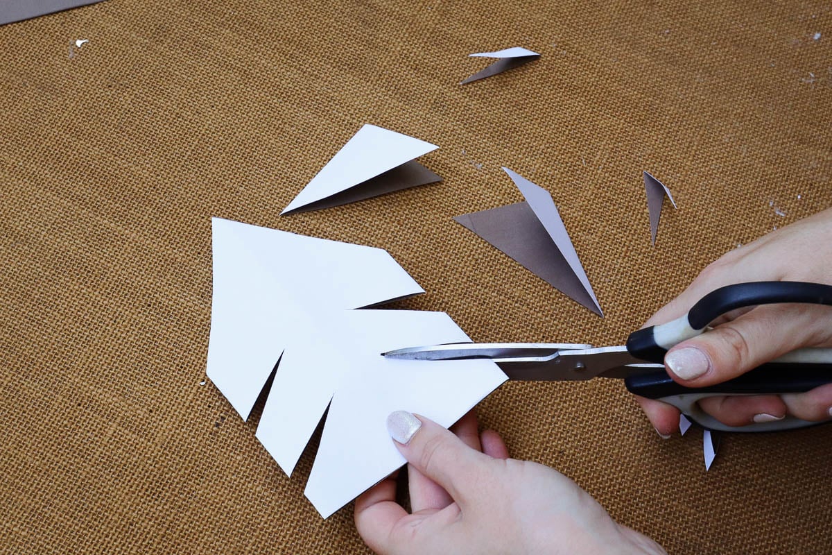 Woman's hand cutting notches out of folded paper.