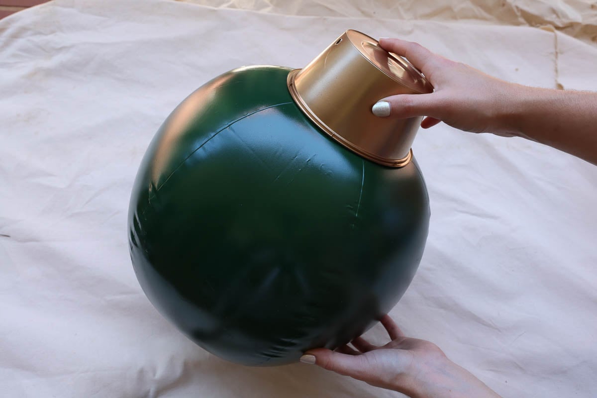Woman's hand placing painted dish on painted beach ball to create a Christmas bauble