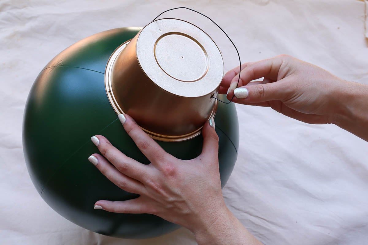 woman's hands placing a piece of wire in top of Christmas bauble