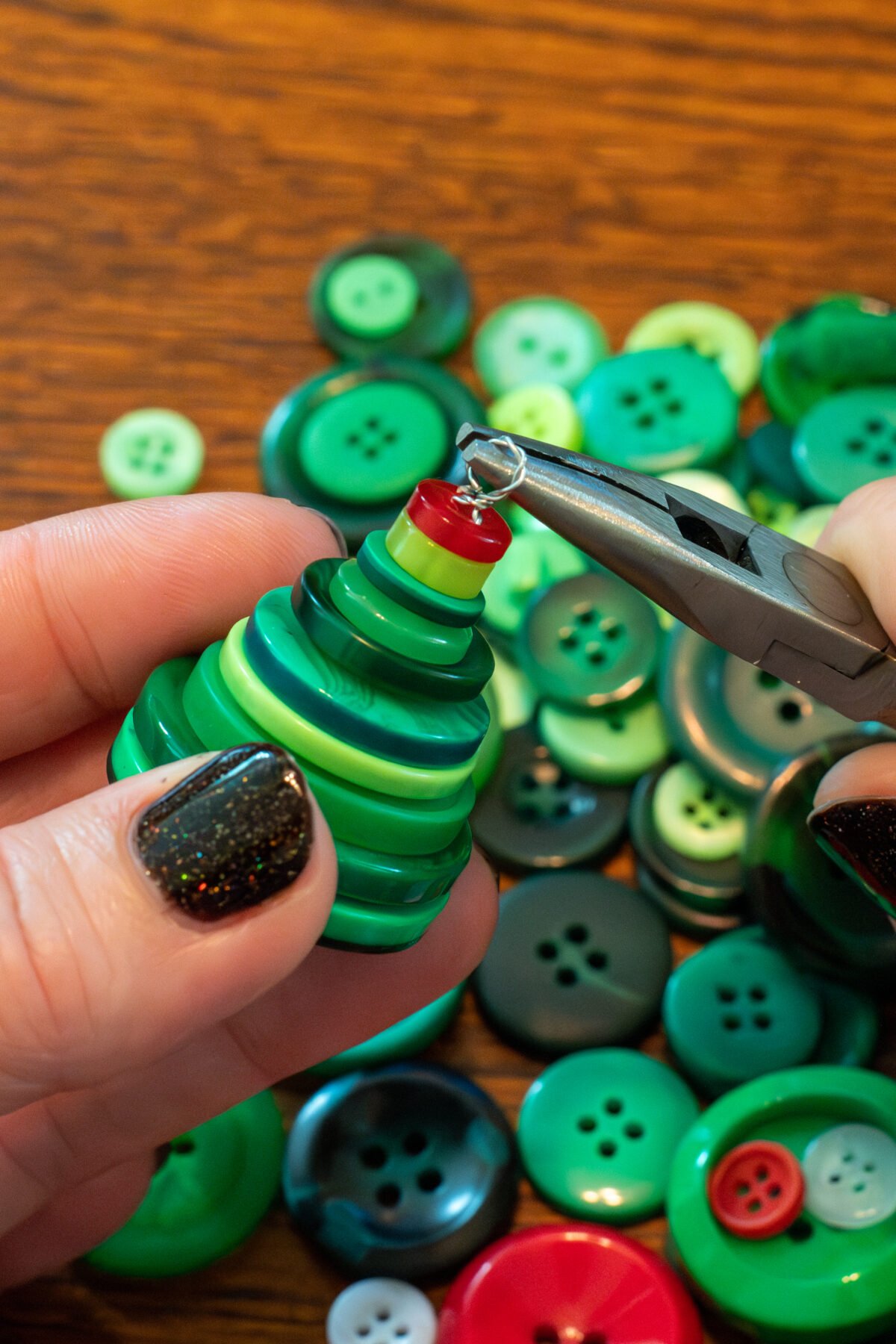 Woman's hands using pliers to make a loop on a finished ornament.