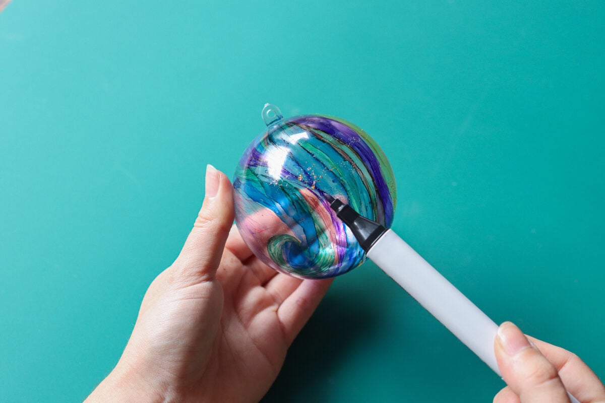 hands using a marker to paint a Christmas bauble