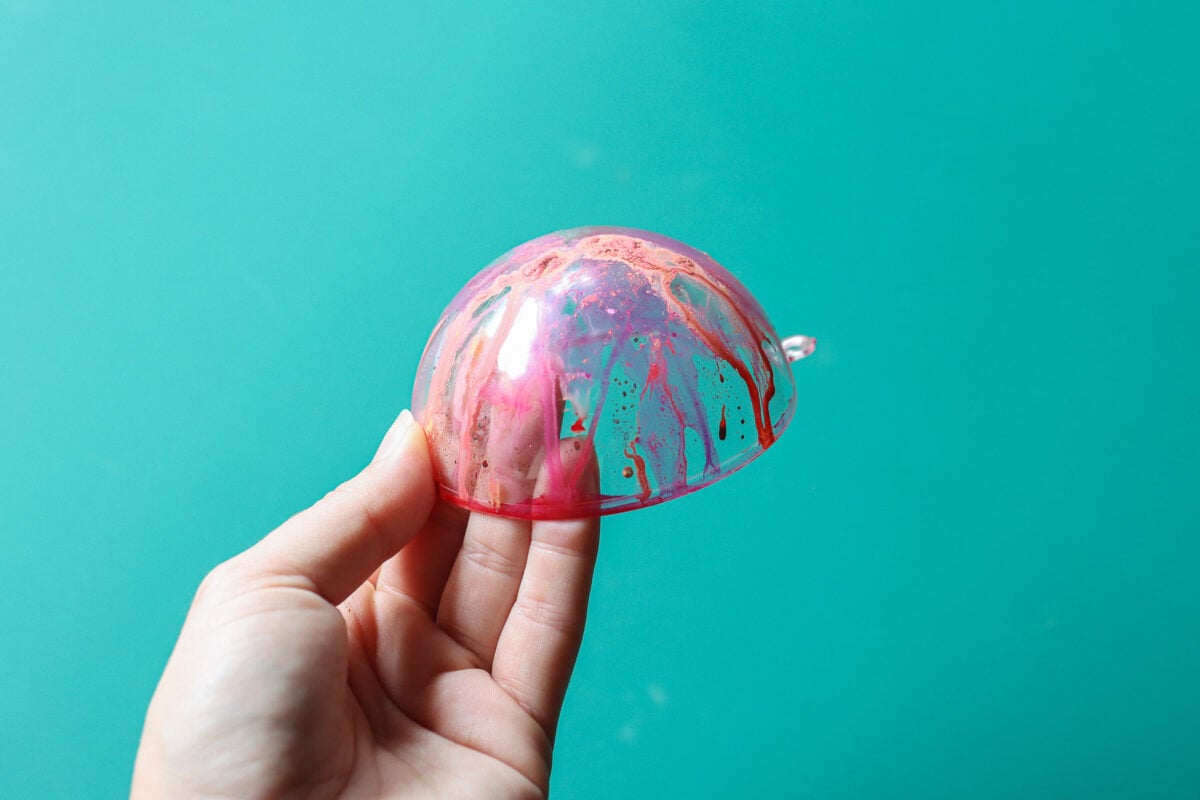 Hand holding half of a Christmas bauble with paint on it