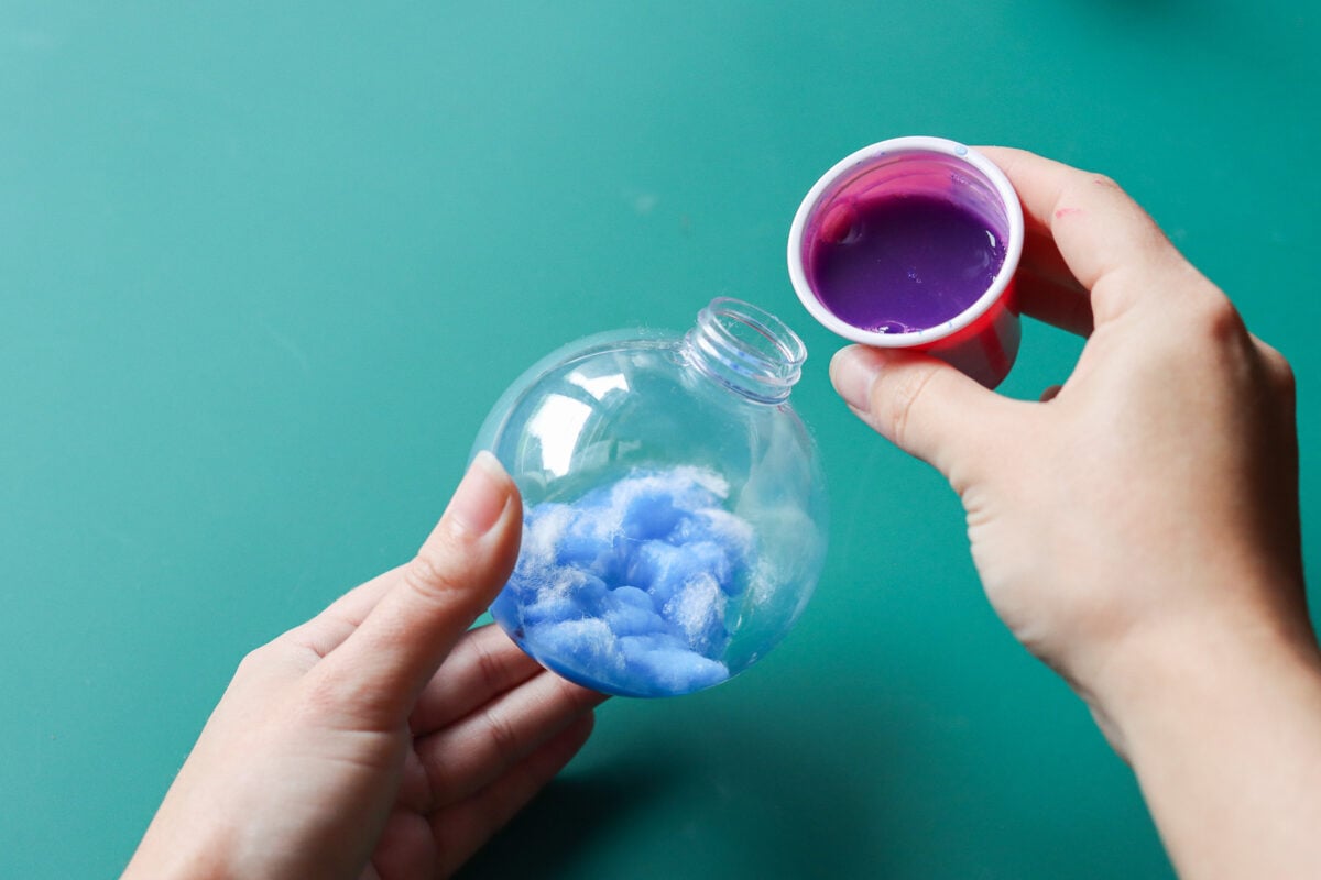 Woman's hand pouring paint into Christmas bauble