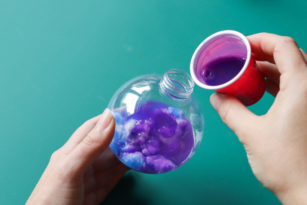 Woman's hand pouring paint into Christmas bauble