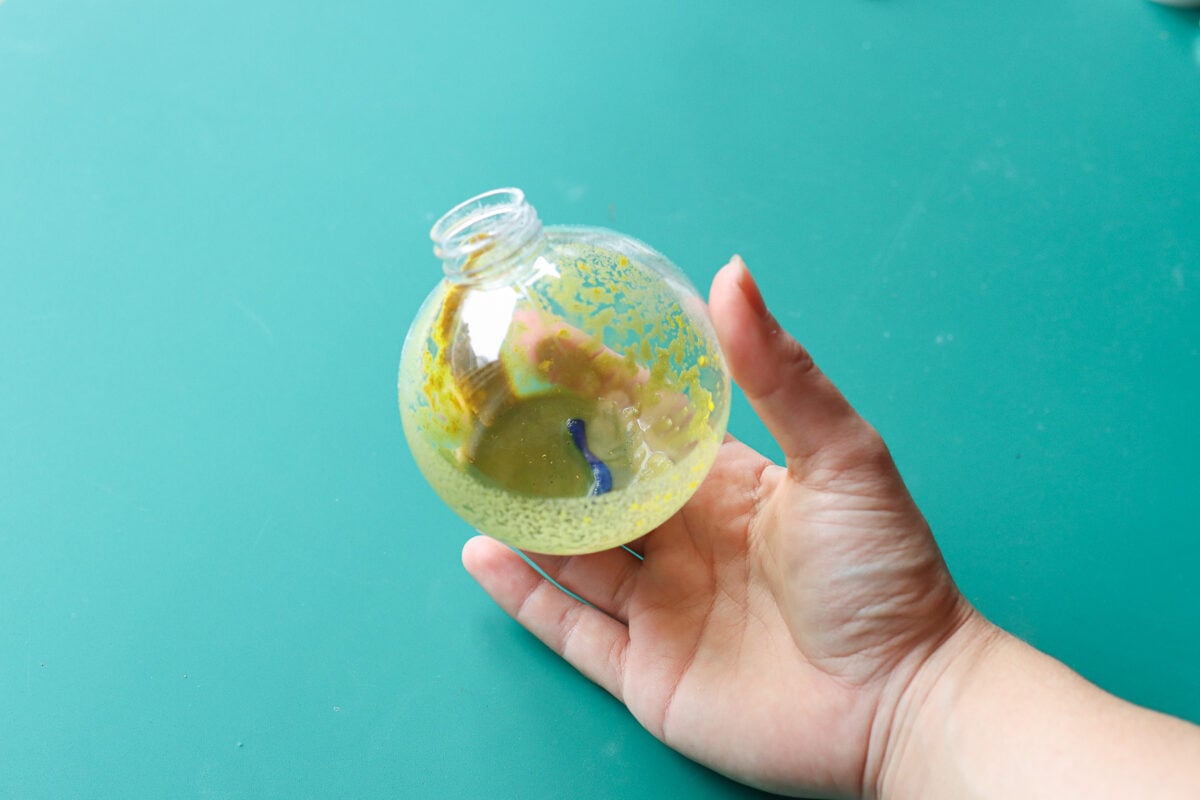 woman's hand holding Christmas bauble filled with paint and baking soda