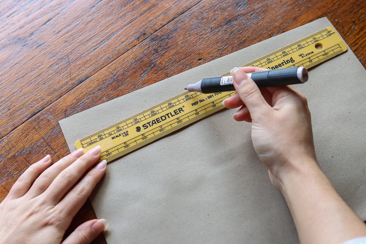 woman's hand measuring brown paper with ruler