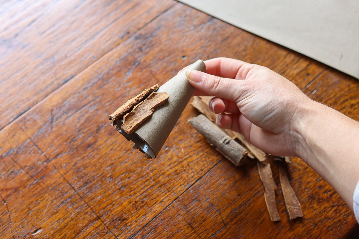 Gluing cinnamon sticks to cardboard cone