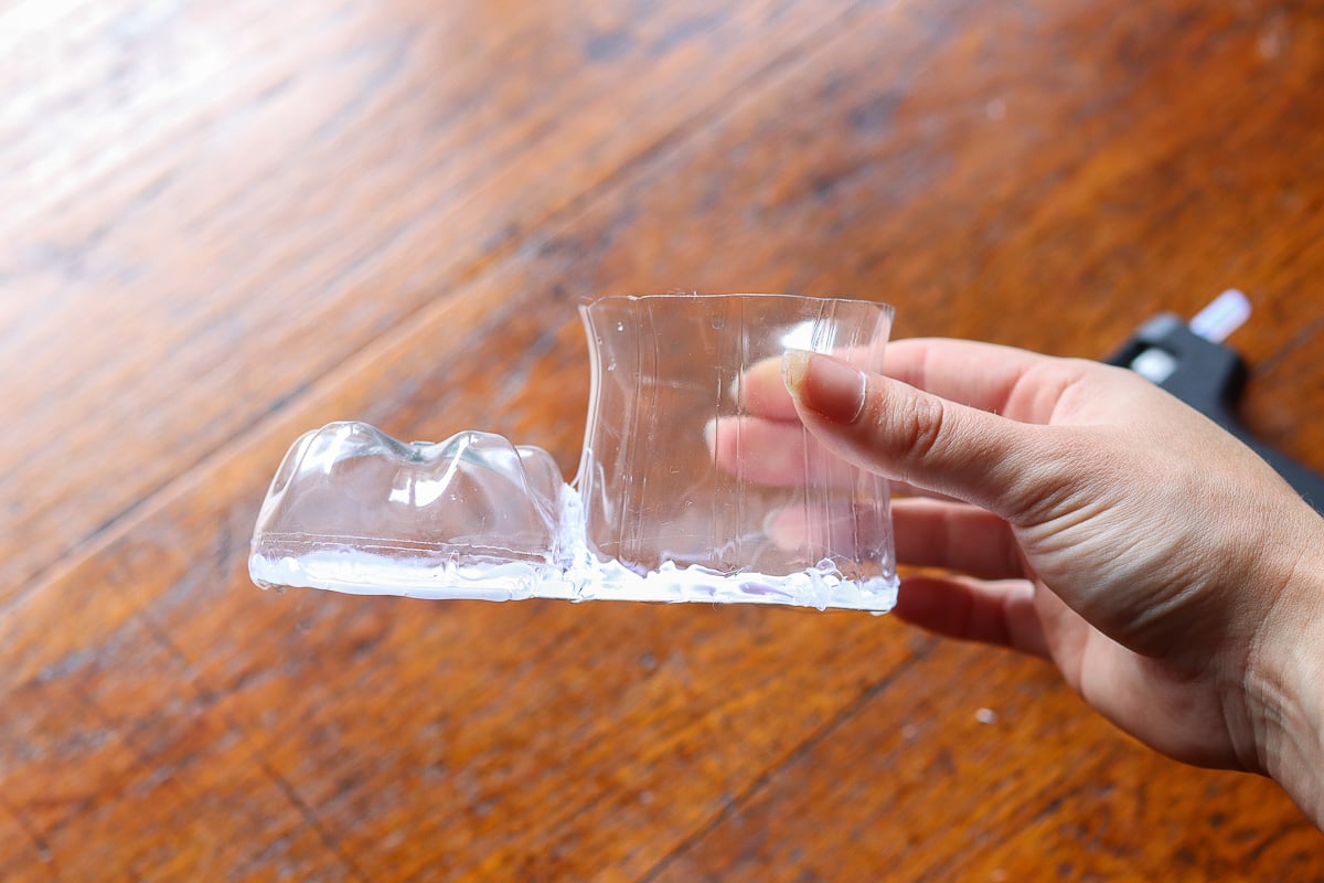 Woman's hand holding boot form made with old soda bottle and cardstock