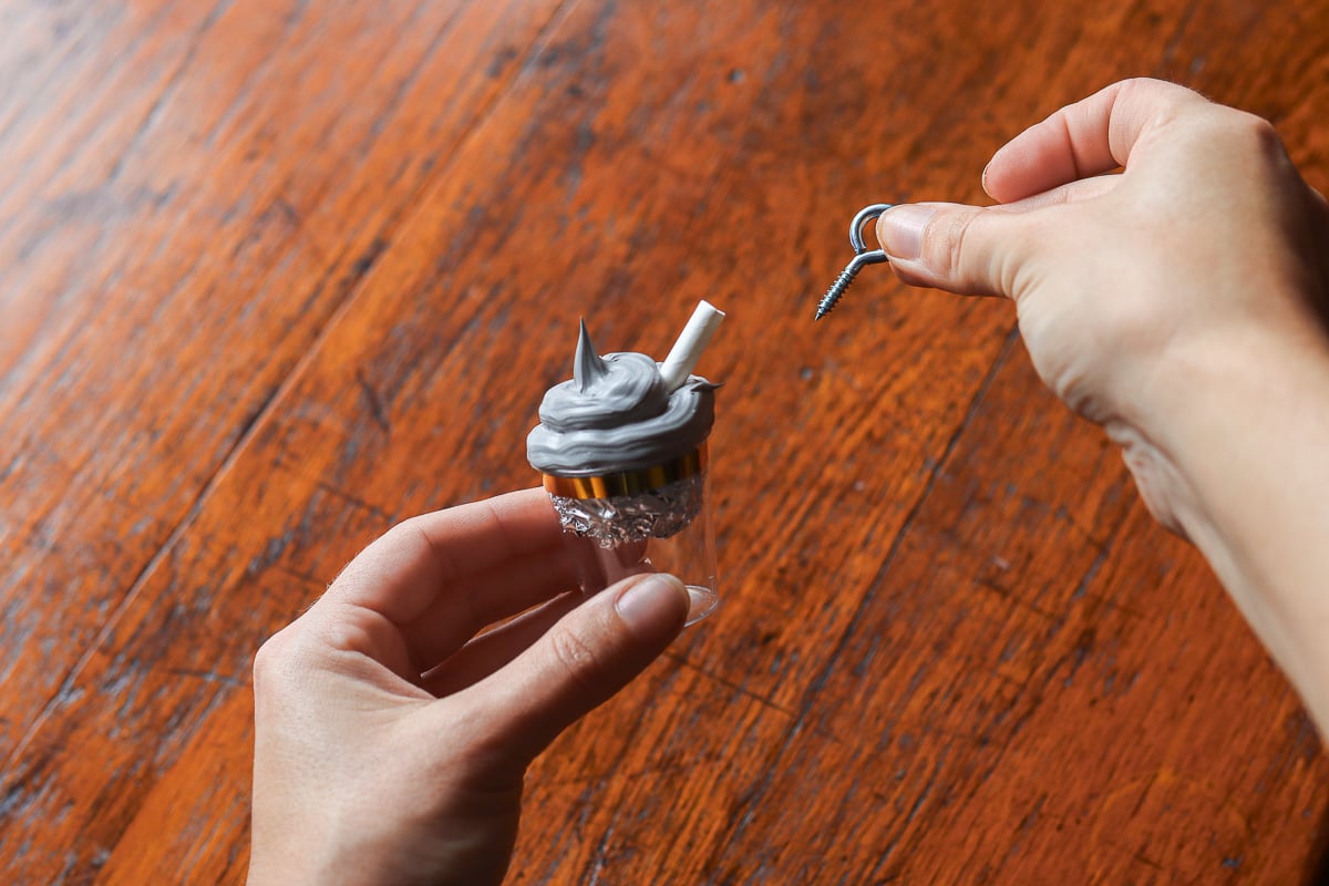 Woman's hands holding hot chocolate ornament in progress and an eye screw