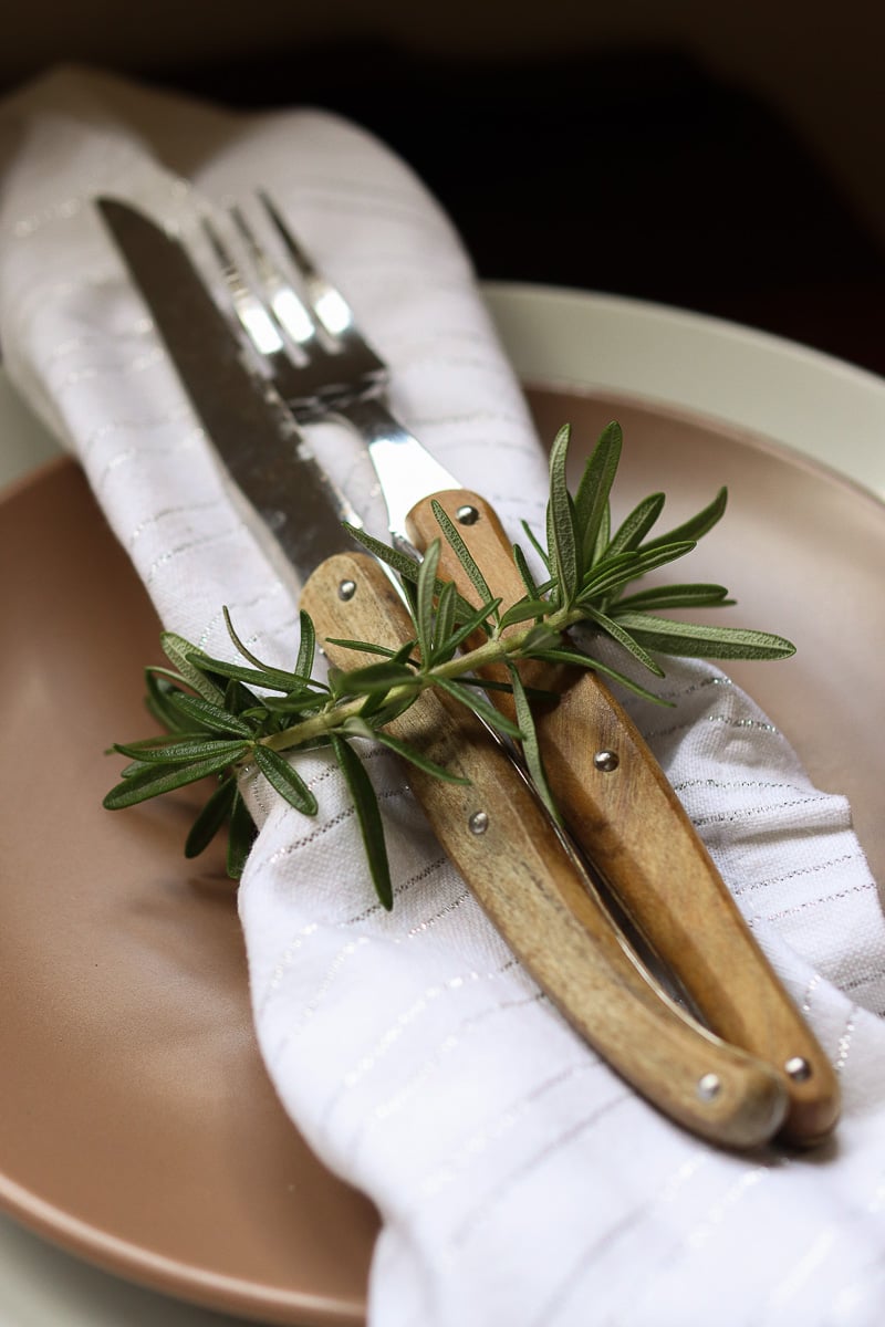 Place setting with rosemary sprig tied around cutlery