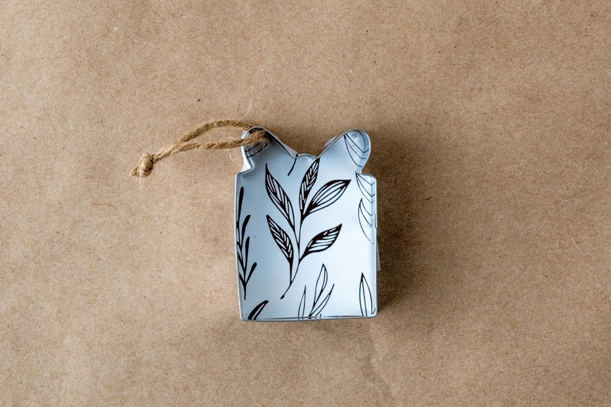 Metal ornament with botanical line art and twine