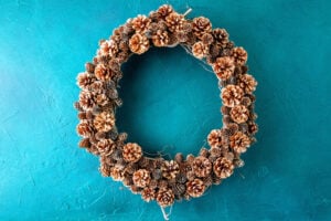 Completed pinecone wreath on teal textured wall