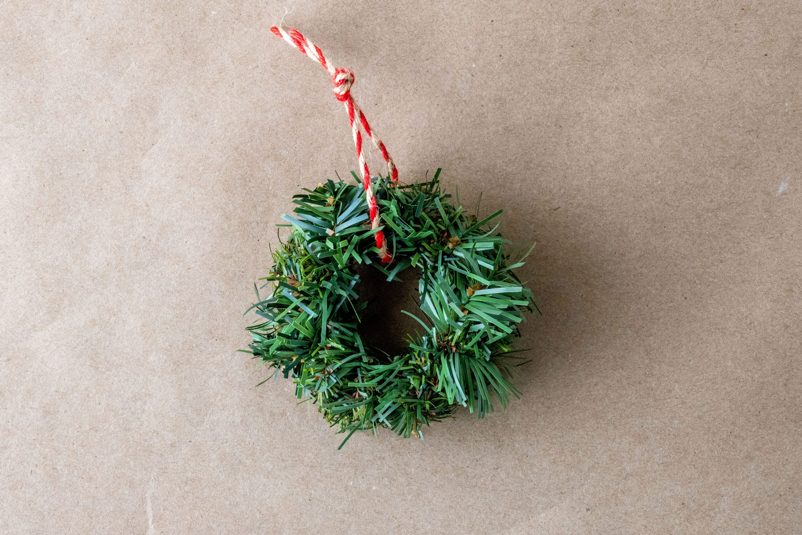Miniature faux pine wreath with red string loop